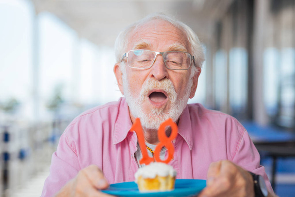 Portrait of a nice aged man blowing at the candles - Фото, зображення