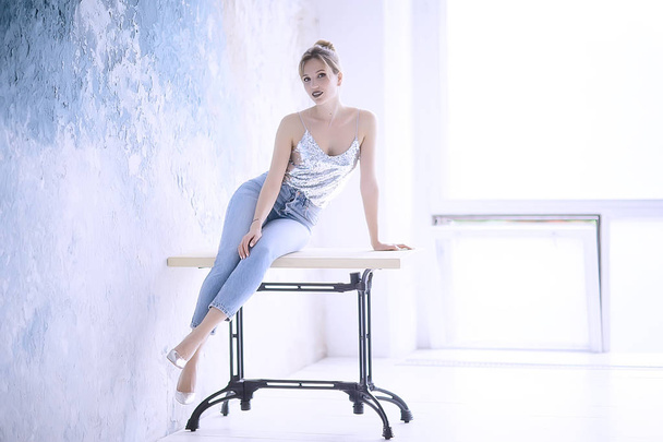 attractive young woman wearing slim jeans posing leaning against wall  - 写真・画像
