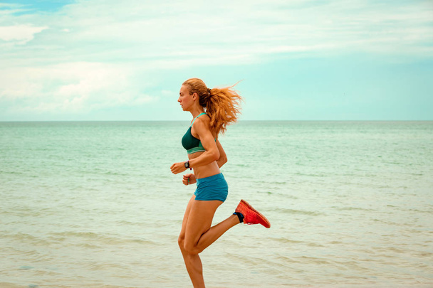 Hermosa mujer deportiva corriendo a lo largo de la hermosa playa de arena, estilo de vida saludable, disfrutando de vacaciones de verano activas cerca del mar
 - Foto, imagen