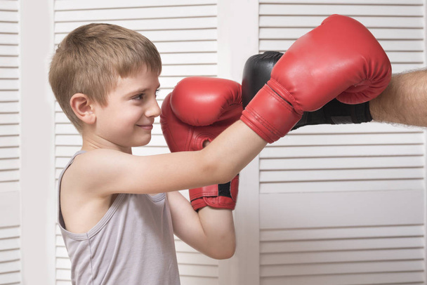 Хлопчик в боксерських рукавичках бореться з чоловічою рукою в рукавичці
. - Фото, зображення