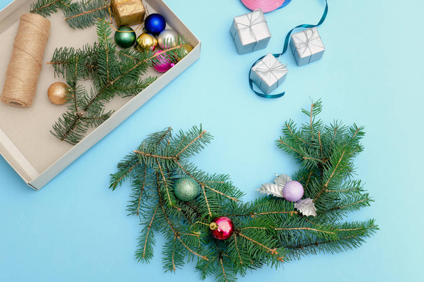 Preparation for Christmas wreath. Spruce branch, ornaments.  Blue background. - Zdjęcie, obraz
