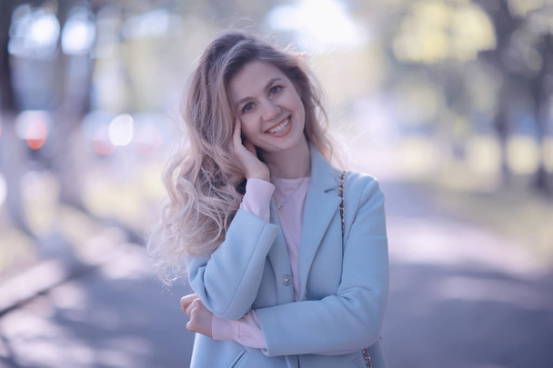 beautiful blonde woman wearing stylish blue coat in park - 写真・画像