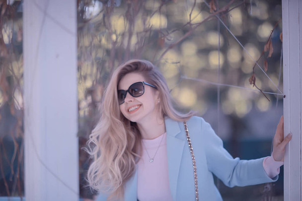 beautiful blonde woman wearing stylish blue coat in park - 写真・画像
