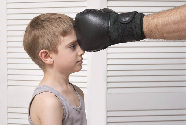 Man's hand in a boxing glove and defenseless child. - Zdjęcie, obraz