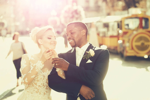Happy african American groom and cute bride walking on street - 写真・画像
