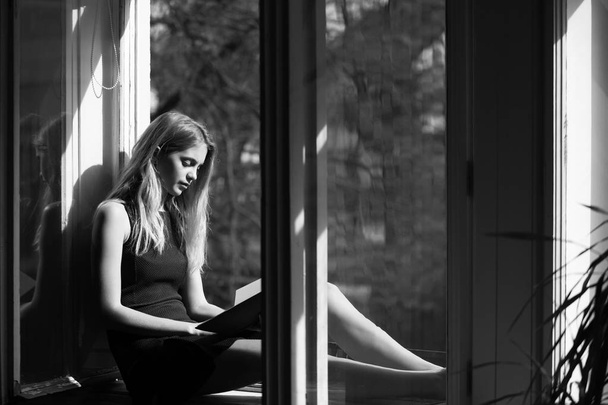 Pretty girl reading book at open window - Foto, immagini