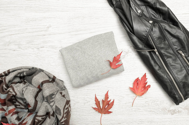 Серый свитер с пространством для текста, черная куртка, шарф и осенние листья. Модная концепция
 - Фото, изображение