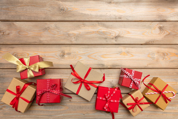 Weihnachtszeit. Geschenkschachteln mit roten Bändern auf hölzernem Hintergrund, Kopierraum, Draufsicht - Foto, Bild