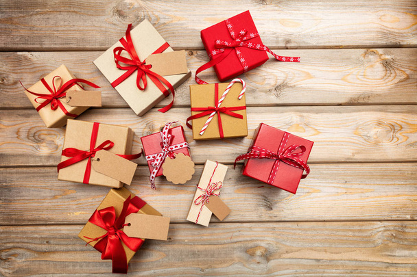 Κουτιά δώρων Χριστουγέννων με κόκκινες κορδέλες και κενές ετικέτες σε ξύλινο υπόβαθρο, διάστημα αντίγραφο, κάτοψη - Φωτογραφία, εικόνα