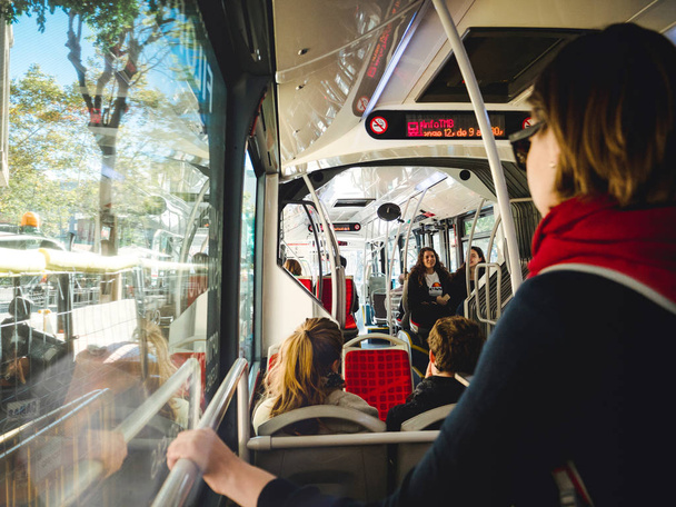 BARCELONA, SPAGNA - 12 NOV 2018: Donna che tiene il manubrio mentre fa il pendolare in autobus pubblico a Barcellona con i passeggeri dei pendolari sullo sfondo che si preparano ad uscire alla stazione degli autobus
 - Foto, immagini