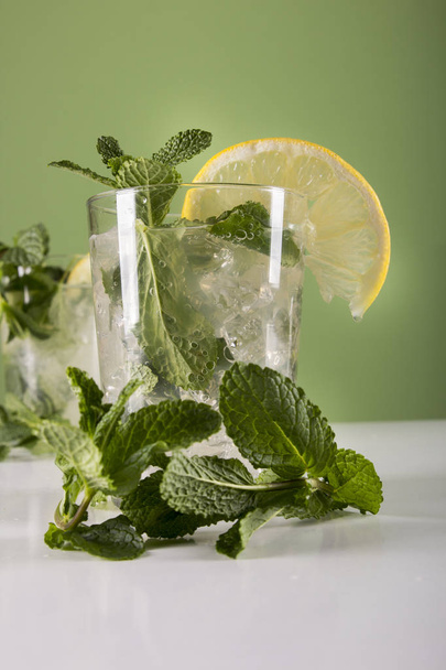 glasses with green Mojito Cocktails drinks, lemons and mint leaves  - Фото, изображение