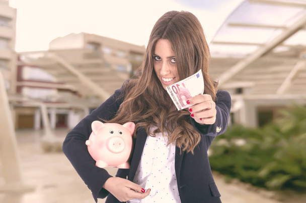 Mooie Hispanic zakenvrouw holding piggy bank  - Foto, afbeelding