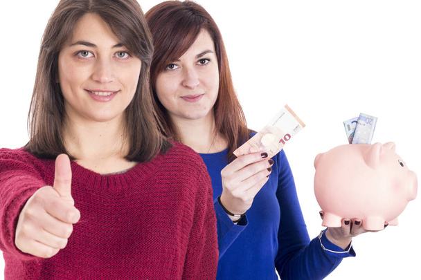 mulheres no estúdio com dinheiro, mealheiro mostrando polegares para cima
  - Foto, Imagem