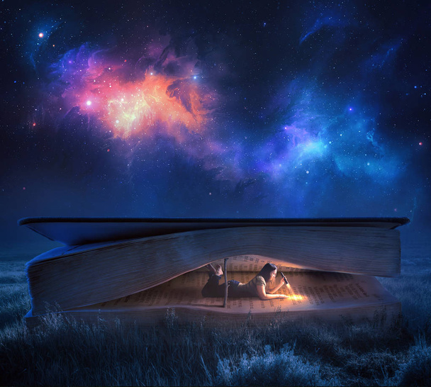 A woman reads a large Bible at night under the stars - Photo, Image