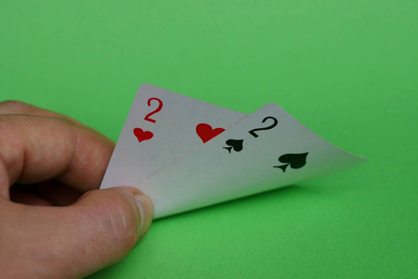 two playing cards in fingers of hands on a green background - Photo, Image