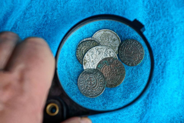 παλιά ασημένια και χάλκινα νομίσματα κάτω από ένα μεγεθυντικό φακό σε ένα μπλε μάλλινο ύφασμα - Φωτογραφία, εικόνα