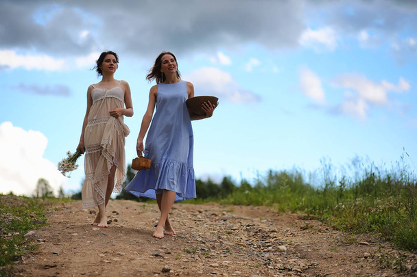 Duas meninas bonitas em vestidos no campo de verão com bagas
 - Foto, Imagem