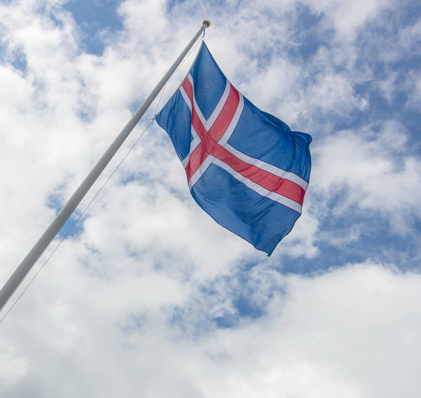 Iceland flag of red and white cross on blue backgroumd hanging proudly in the windy Icelandic weather - Foto, imagen