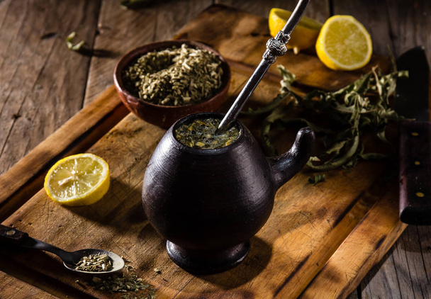Yerba mate - Latin American hot drink herb tea in clay mug on wooden table - Valokuva, kuva