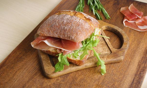 sandwich with prosciutto jamon on a wooden background - Photo, image
