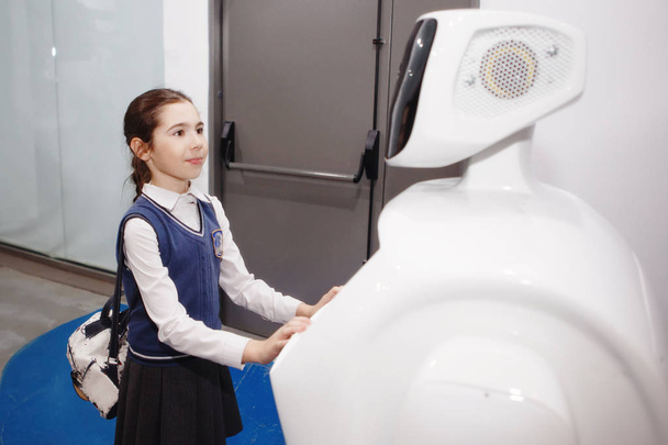 ein Mädchen kommuniziert mit einem Roboter auf einer Ausstellung wissenschaftlicher Errungenschaften. - Foto, Bild