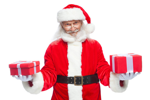 Kerstmis. Glimlachend Santa Claus in witte handschoenen houdt twee dozen met geschenken. Het concept van het kiezen van een gift, gulle giften. Geïsoleerd op witte achtergrond. - Foto, afbeelding
