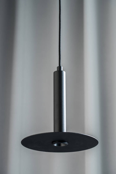 Black metallic lamp hanging on gray curtain background - Fotoğraf, Görsel