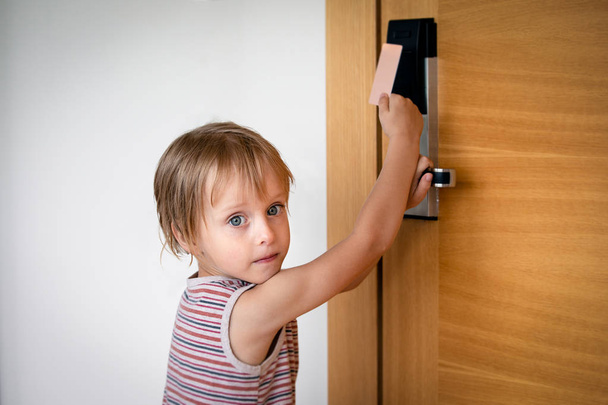Μικρό αγόρι προσπαθεί να ανοίξει τις πόρτες με κλειδαριά με κάρτα στο ξενοδοχείο - Φωτογραφία, εικόνα