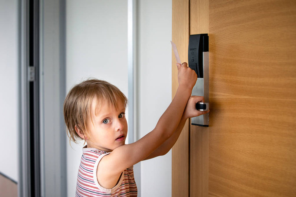 Niño tratando de abrir puertas con cerradura de tarjeta en el hotel
 - Foto, imagen