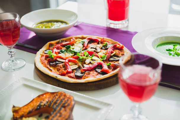 Table au café avec des plats végétariens - pizza, citrouille grillée, tarte et boissons sucrées
. - Photo, image