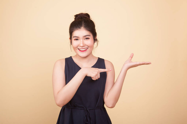Beautiful young Asian woman point to palm hand  on beige background - Φωτογραφία, εικόνα