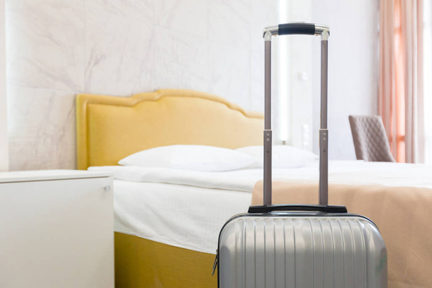 Grey luggage bag near bed in hotel room - Fotografie, Obrázek