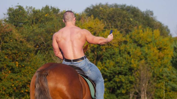Homme athlétique à dos nu fort chevauchant un cheval dans la nature
 - Photo, image