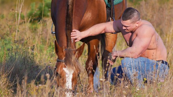A csupasz törzs guggolás mellett a lovat és a ló simogatás testépítő férfi - Fotó, kép