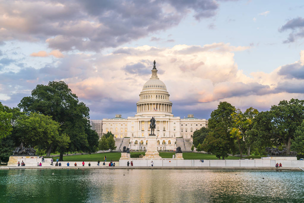 El edificio del Capitolio de Estados Unidos al atardecer irradia reflejo en el agua
. - Foto, imagen