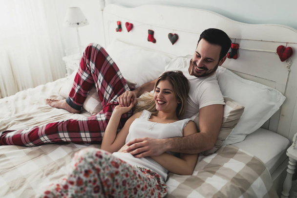 Young attractive happy couple having romantic time in bed - Fotó, kép