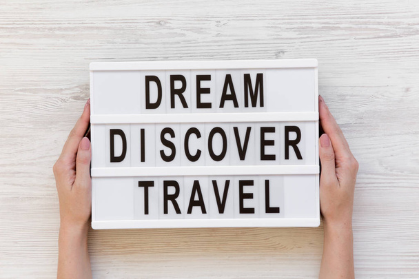 Female hands hold modern board with text 'Dream Discover Travel', top view. Overhead, from above. - Foto, imagen