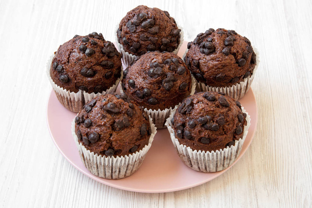 Chocolate muffins on pink plate on white wooden surface, side view. Closeup. - Φωτογραφία, εικόνα