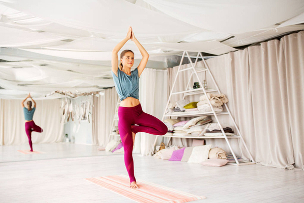 young woman doing yoga tree pose at studio - Photo, image