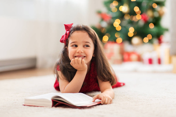 happy girl reading book at home on christmas - Photo, image
