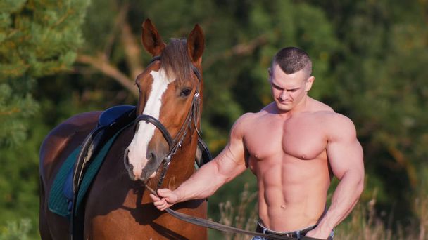 Testépítő férfi egy csupasz törzs állt a ló mellett tárolás a ló mellett a kötél. - Fotó, kép