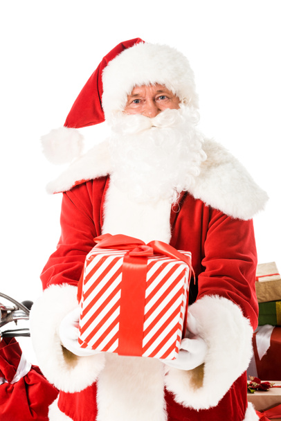 Санта-Клаус с полосатой подарочной коробкой и глядя на камеру, изолированную на белом
 - Фото, изображение