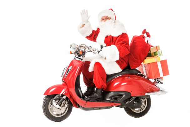 Санта Клаус ездит на винтажном красном скутере и машет на камеру изолированы на белом
 - Фото, изображение