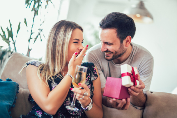 lachende jongeman verrassende vrolijke vrouw met een doos van de gift thuis - Foto, afbeelding