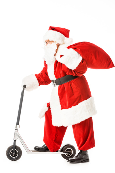 side view of santa claus with sack riding scooter isolated on white - Photo, Image
