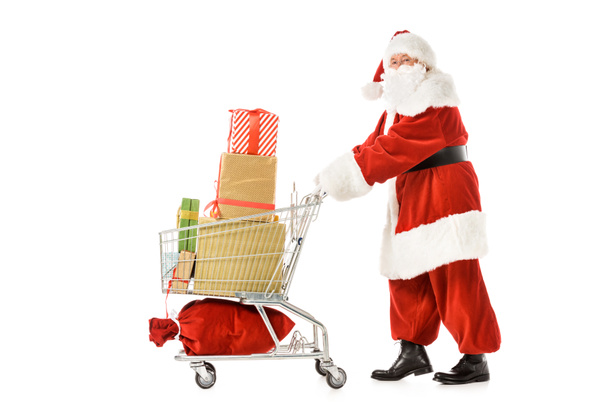 side view of santa claus walking with shopping cart full of gift boxes isolated on white - Fotografie, Obrázek