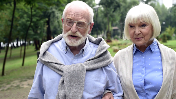 улыбающаяся пожилая пара гуляющая и разговаривающая в парке
 - Кадры, видео