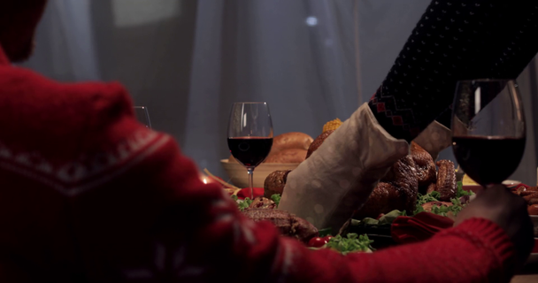 rajattu näkymä aviomies istuu lasin viiniä, kun vaimo tarjoilee pöydän paistettua kalkkunaa kiitospäivänä
 - Materiaali, video