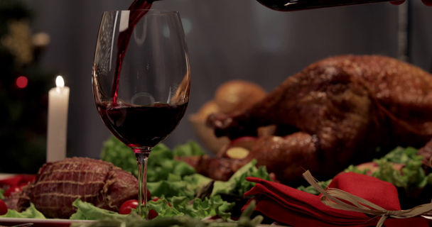 обрезанный вид женщины, наливающей красное вино в бокал, запечённой индейки на обеденный стол в День Благодарения
 - Кадры, видео