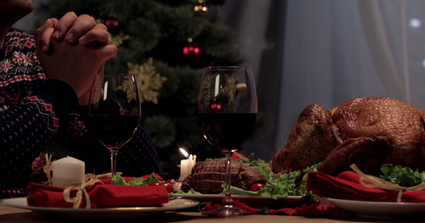 vista recortada de marido rezando, esposa poniendo pavo horneado en la mesa de la cena en el Día de Acción de Gracias
 - Metraje, vídeo